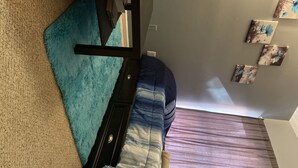 A room with a bed, a blue furry rug, a blue vase with flowers, and wall art. - A cozy little place with 2 bedrooms all to yourself (Hartford)