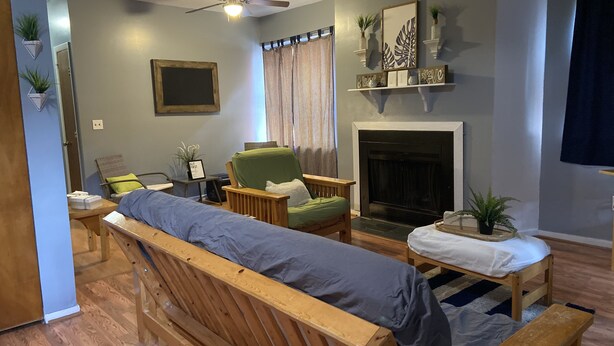 A cozy living room with a wooden bench, a green armchair, a fireplace, and a ceiling fan. - A cozy little place with 2 bedrooms all to yourself (Hartford)