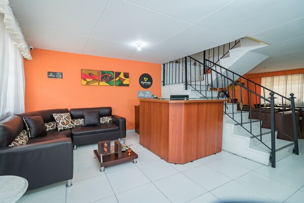Un salón con sofá, mesa de centro y mostrador de recepción de madera.