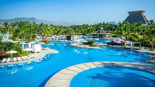 A large swimming pool with multiple lanes, surrounded by palm trees and lounge chairs. - Mayan Palace In Acapulco inside Vidanta Resort Luxury in your services (Acapulco)