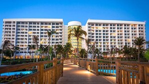 A hotel with multiple high-rise buildings, a wooden boardwalk, and a pool area. - Mayan Palace In Acapulco inside Vidanta Resort Luxury in your services (Acapulco)