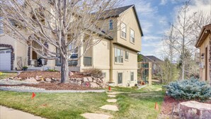 A two-story residential building with a stone foundation, a well-maintained lawn, and a tree in the front yard. - A Little Luxury near the AFA and Ford Amphitheater (Colorado Springs)