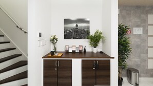 A modern kitchen with a dark wooden countertop, a cityscape photograph above the counter, and a staircase to the left.