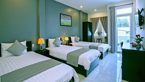A hotel room with three beds, a desk, a chair, and a window with curtains. - Focus Homestay (Da Nang)