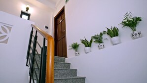A staircase with a wooden handrail, a light fixture above, and potted plants on the landing. - Focus Homestay (Da Nang)