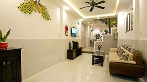 A modern living room with a sofa, a coffee table, a TV, and decorative wall art. - Focus Homestay (Da Nang)