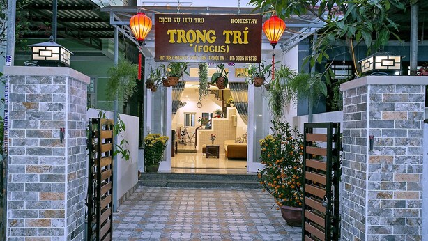 A hotel entrance with a stone facade, a signboard, and potted plants. - Focus Homestay (Da Nang)