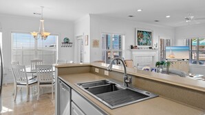 Een moderne keuken met een centraal eiland, witte kasten en een eethoek met stoelen.