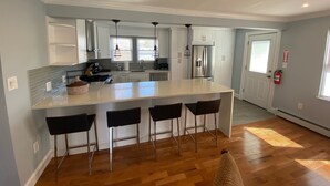 A modern kitchen with a large island, bar stools, and stainless steel appliances.