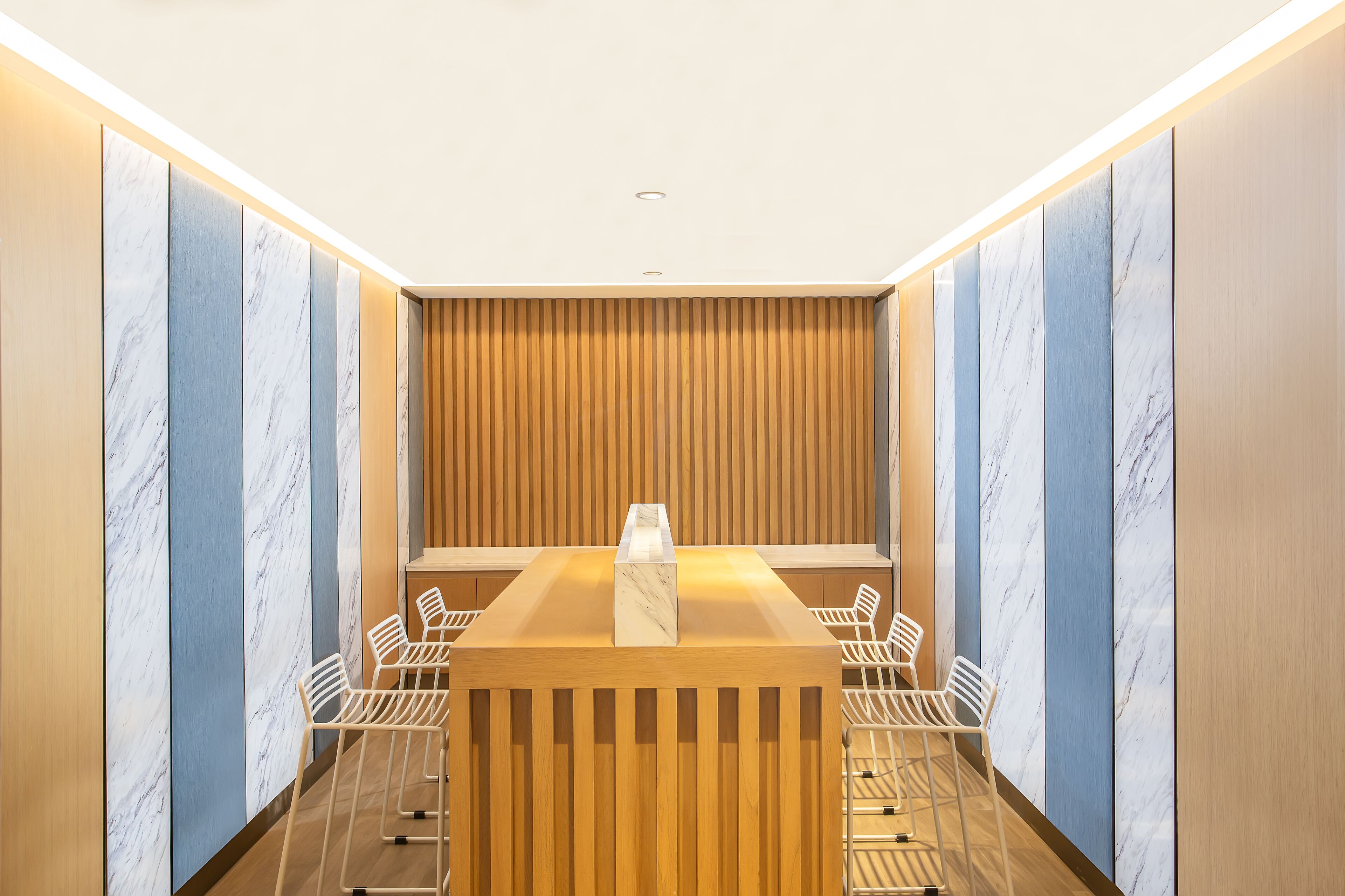 A modern conference room with a wooden reception desk, marble panels, and white chairs.