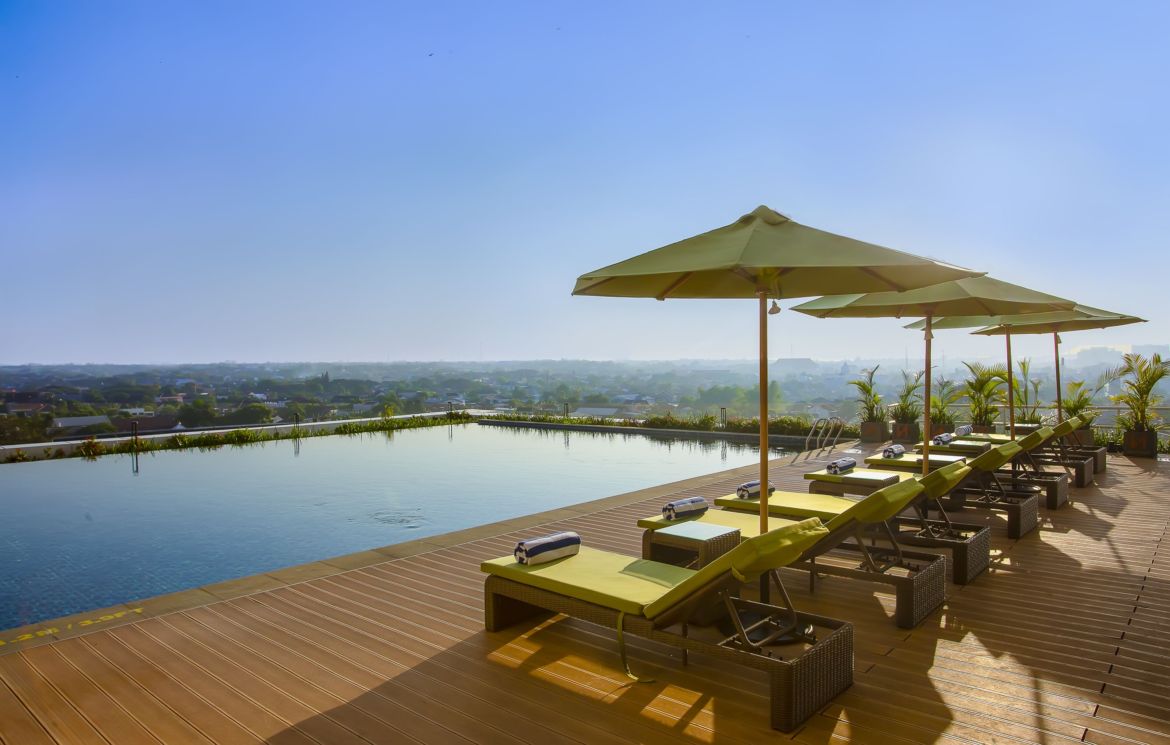 A poolside area with lounge chairs and umbrellas, overlooking a body of water and distant landscape.