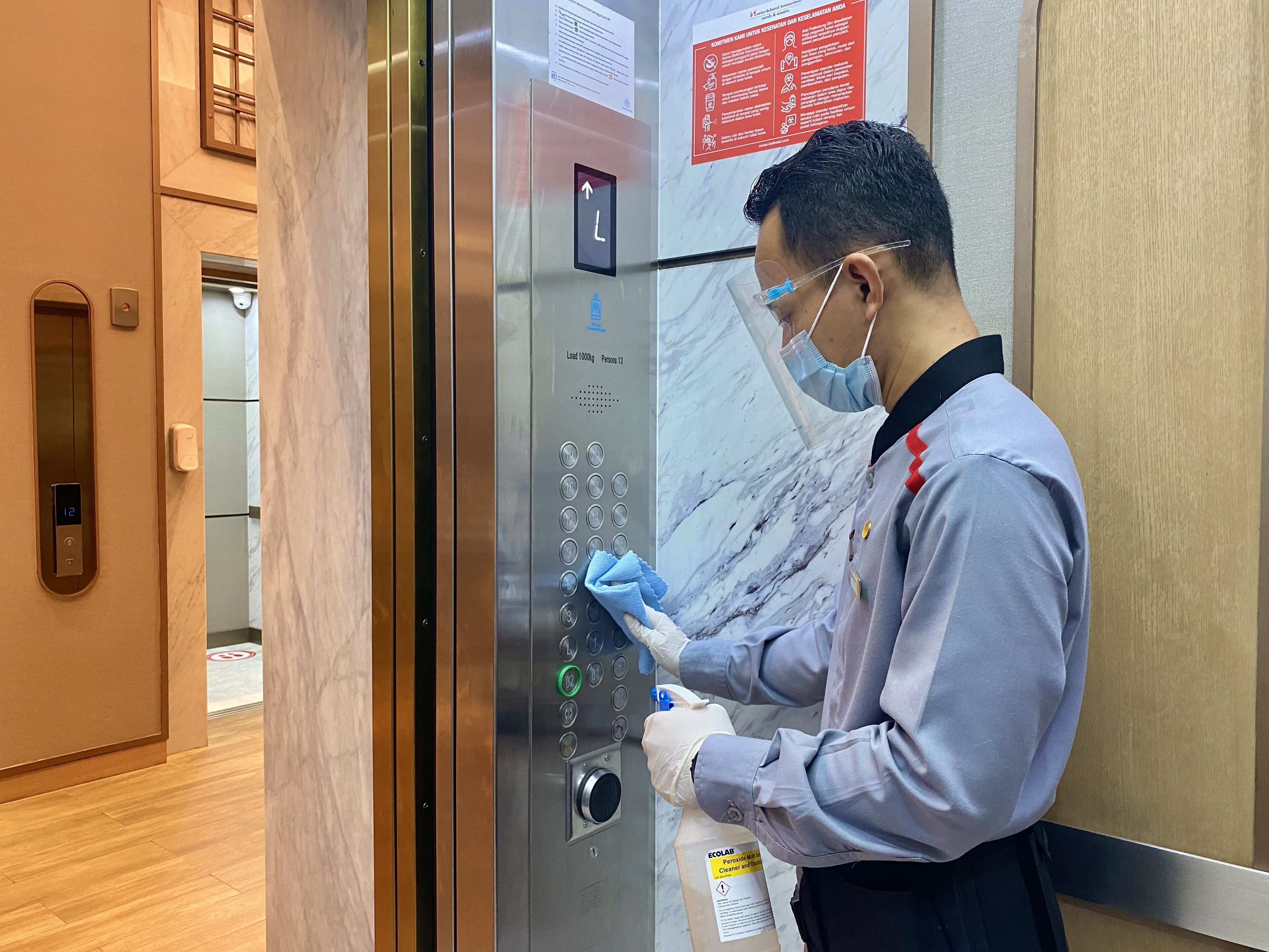 A person cleaning an elevator with a spray bottle.