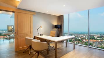 Enjoy a panoramic city view from this office space with a large desk and two chairs.