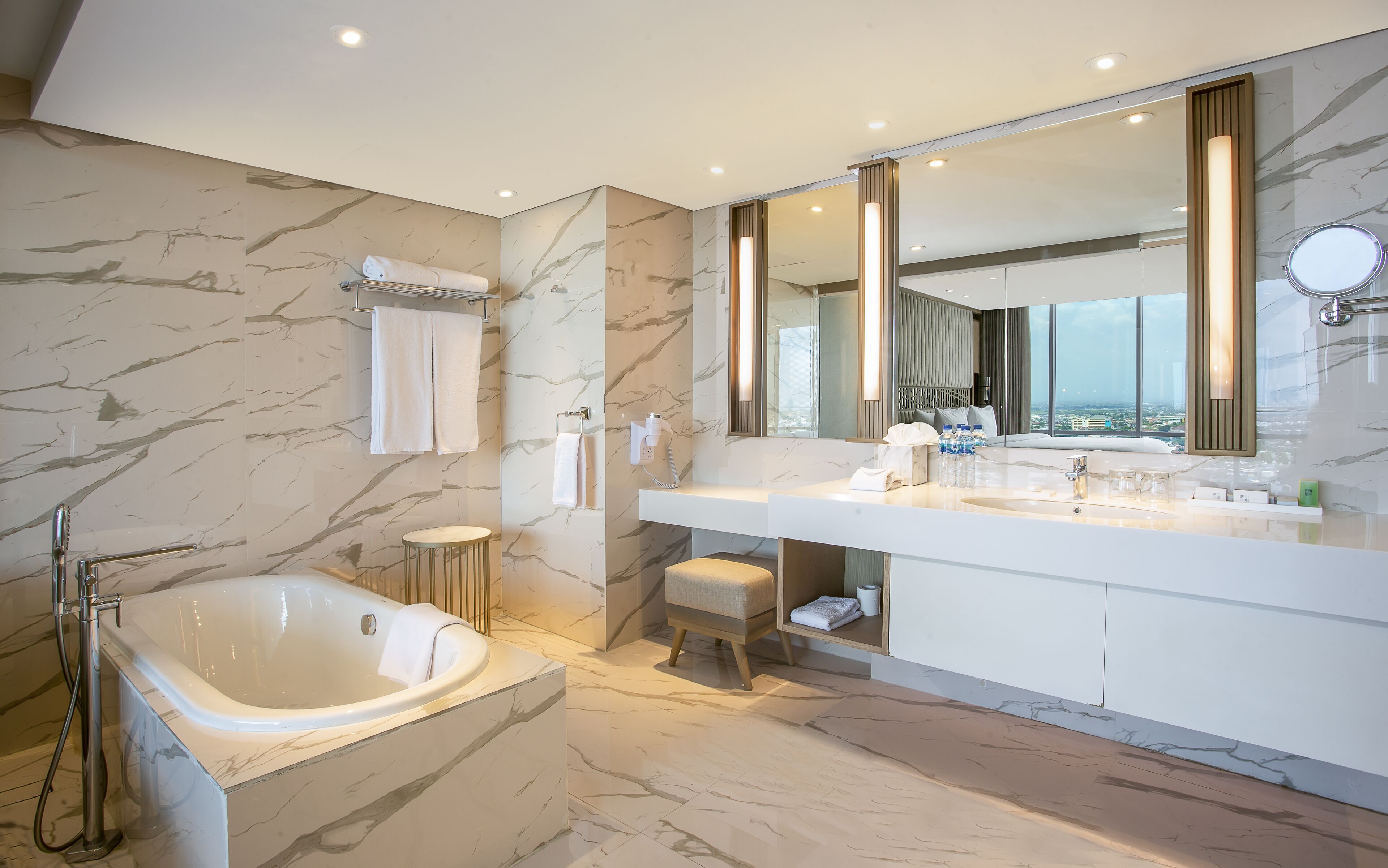 Un baño moderno con bañera, espejo grande y tocador con lavamanos.