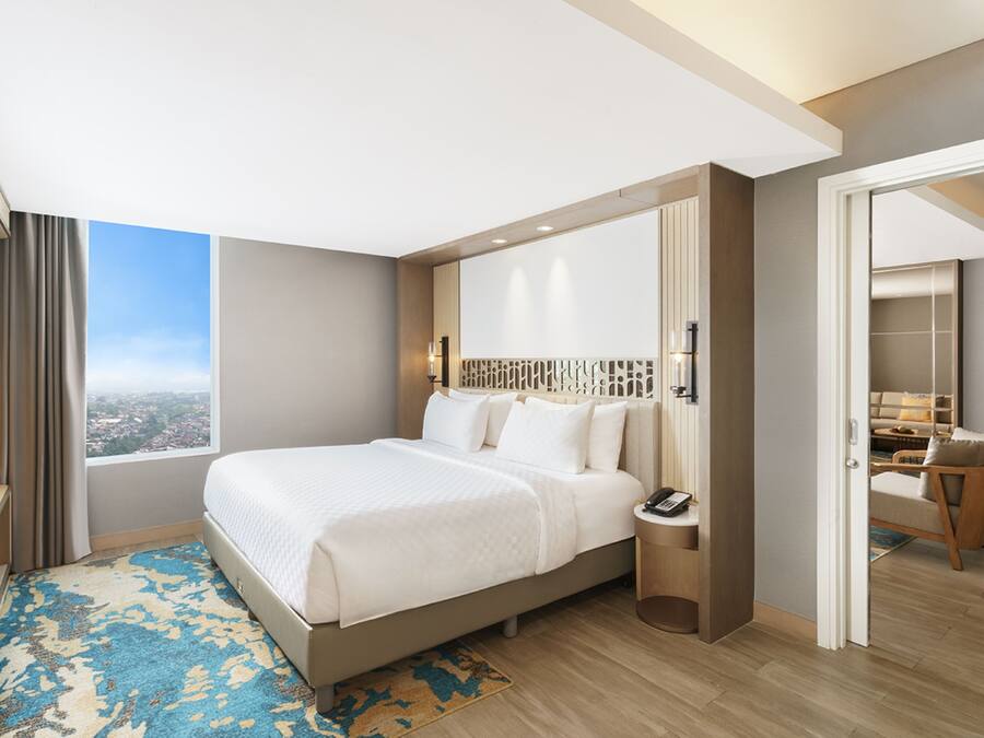 Una habitación de hotel moderna con una cama grande, una mesita de noche y vistas a la ciudad.