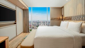 A modern hotel room with a large bed, a flat-screen TV, and a city view. - Swiss-Belhotel Solo (Surakarta)