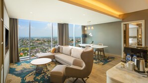 A modern living room with a large sectional sofa, a round coffee table, and a dining area with a table and chairs. - Swiss-Belhotel Solo (Surakarta)