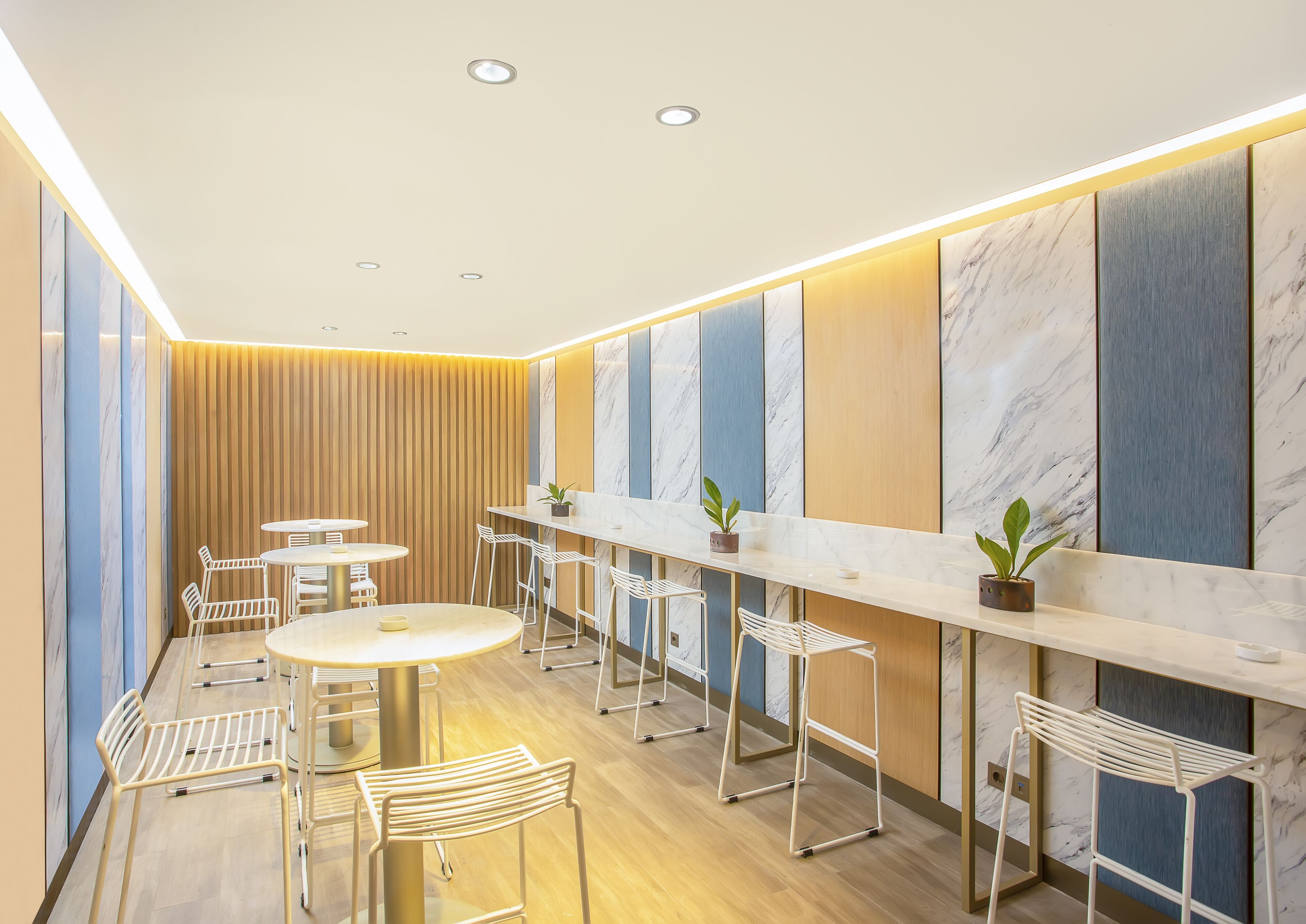 A modern interior with a long counter, white chairs, and a wooden panel wall.