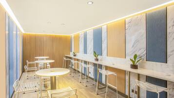 A modern interior with a long counter, white chairs, and a wooden panel wall.
