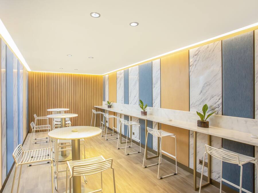 A modern interior with a long counter, white chairs, and a wooden panel wall.