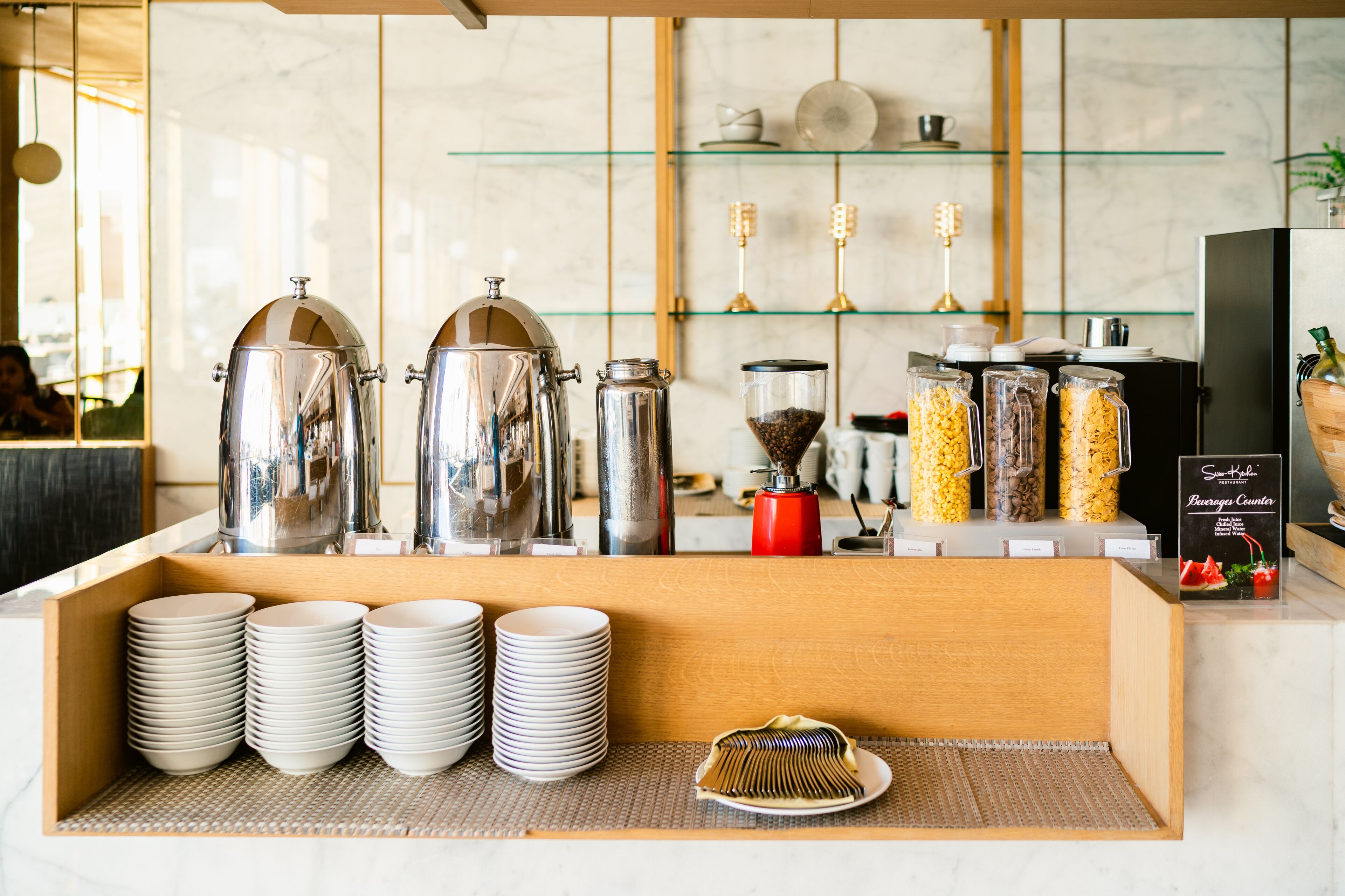Un espace dédié au café, équipé de plusieurs machines à café, d’un moulin à café et d’un buffet où l’on trouve des assiettes empilées et un gâteau.