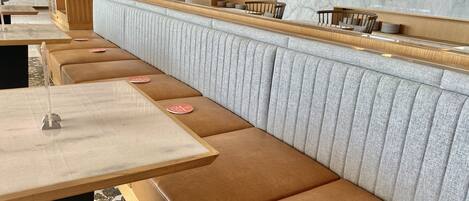 Un restaurante moderno con una barra alargada, asientos acolchados y una distribución limpia y ordenada.
