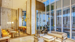 A modern lobby with seating areas, a reception desk, and large windows offering views of the city. - Swiss-Belhotel Solo (Surakarta)