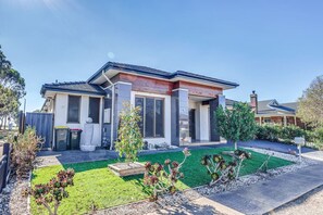 A modern two-story house with a well-maintained lawn and garden.