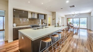 Una cocina moderna con una isla central, taburetes de bar y un comedor con vistas.