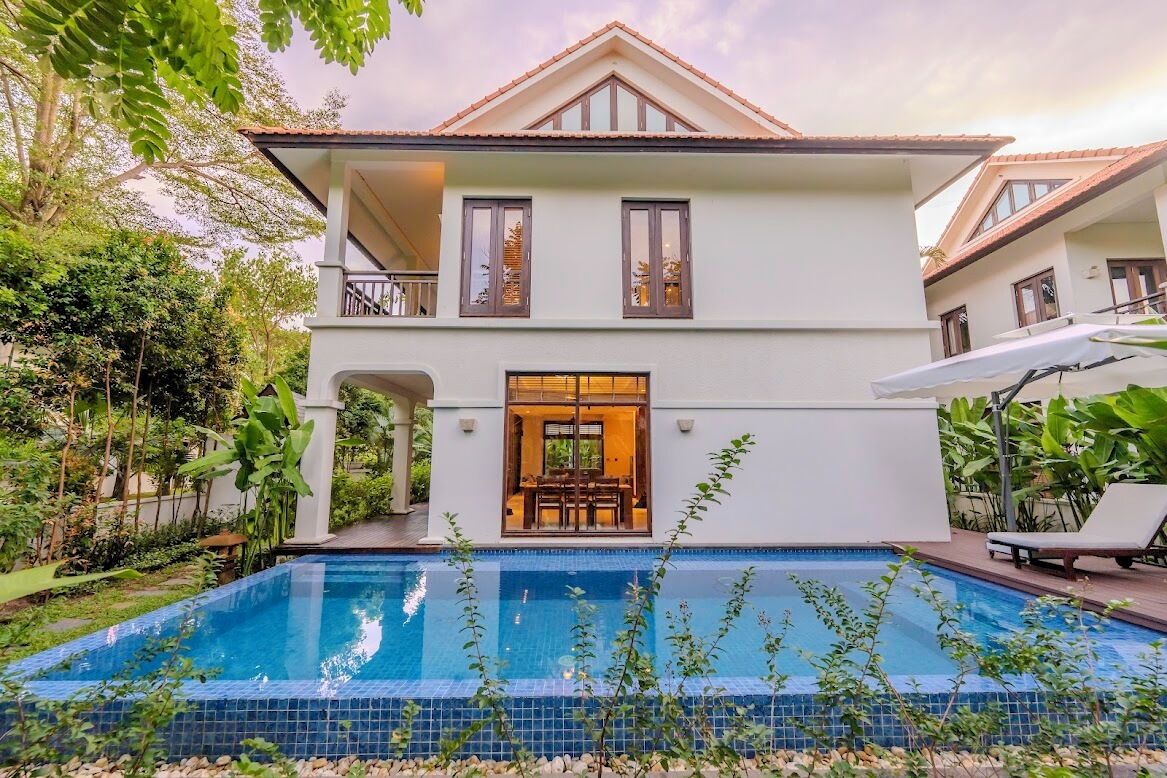 A two-story house with a swimming pool in front.