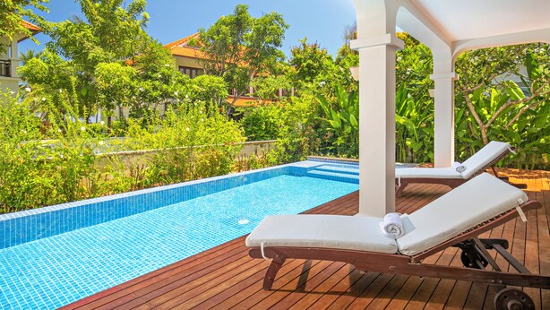 A poolside area with lounge chairs, a wooden deck, and a clear blue pool. - Luxury Villas - Villa Danang Beach (Da Nang)