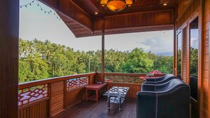 A wooden deck with a table and chairs, overlooking a lush green landscape. - Villa Robert (Manado)