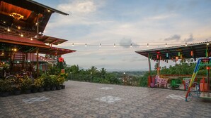 A terrace with patterned flooring, outdoor seating, and a view of the landscape. - Villa Robert (Manado)
