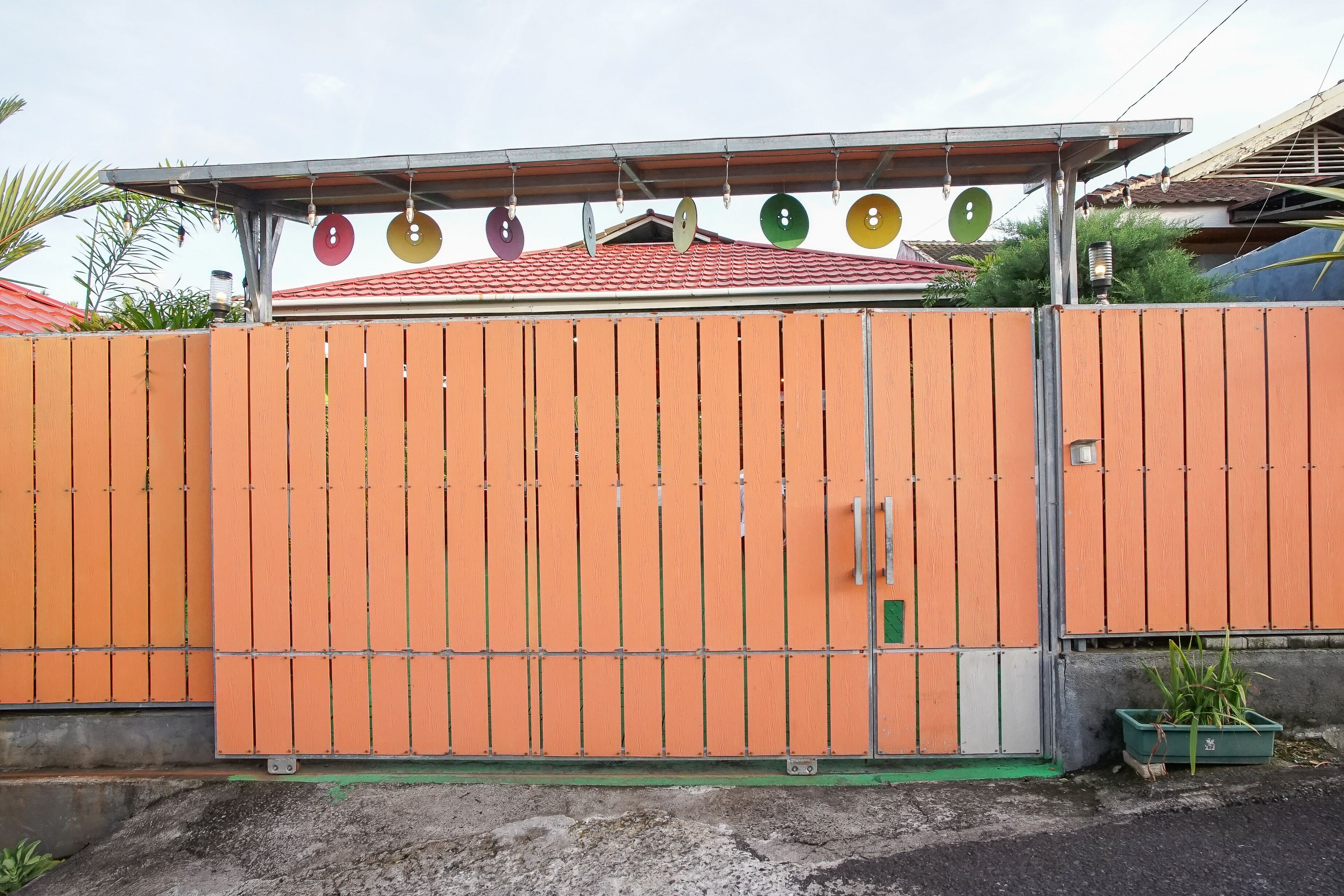 An orange gated property with a metal roof and satellite dishes.
