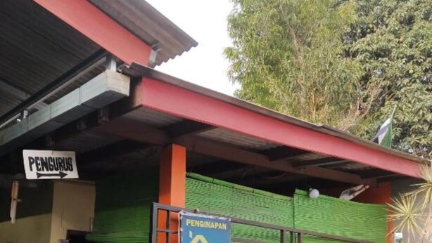 Un bâtiment avec une enseigne indiquant « PENGINAPAN » et une enseigne bleue faisant de la publicité pour « Pramadina », avec la date « 24 JAN ».