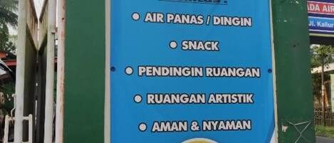 A signboard advertising a 24-hour facility named "PRIMADONA" with amenities like air pans, snacks, resting areas, artistic activities, and a room for men and women.