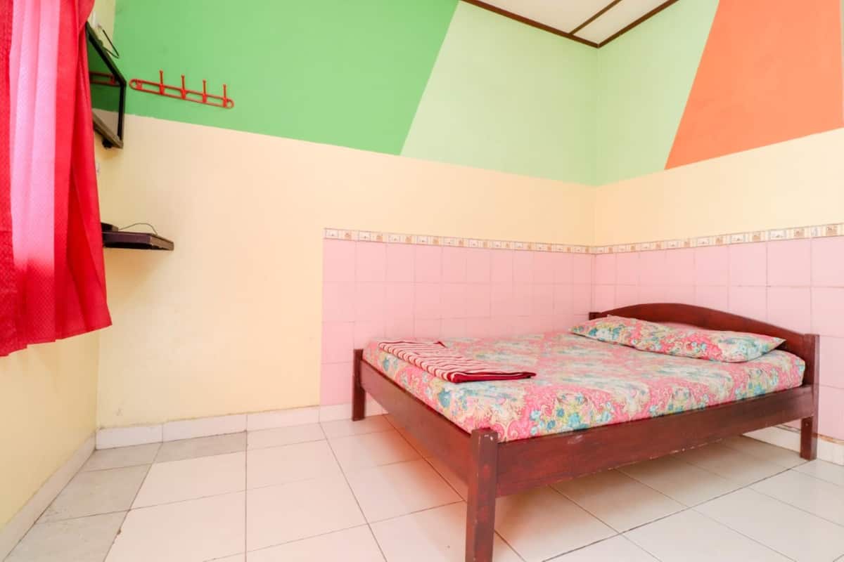 A room with a bed, a red curtain, and a wall-mounted rack.