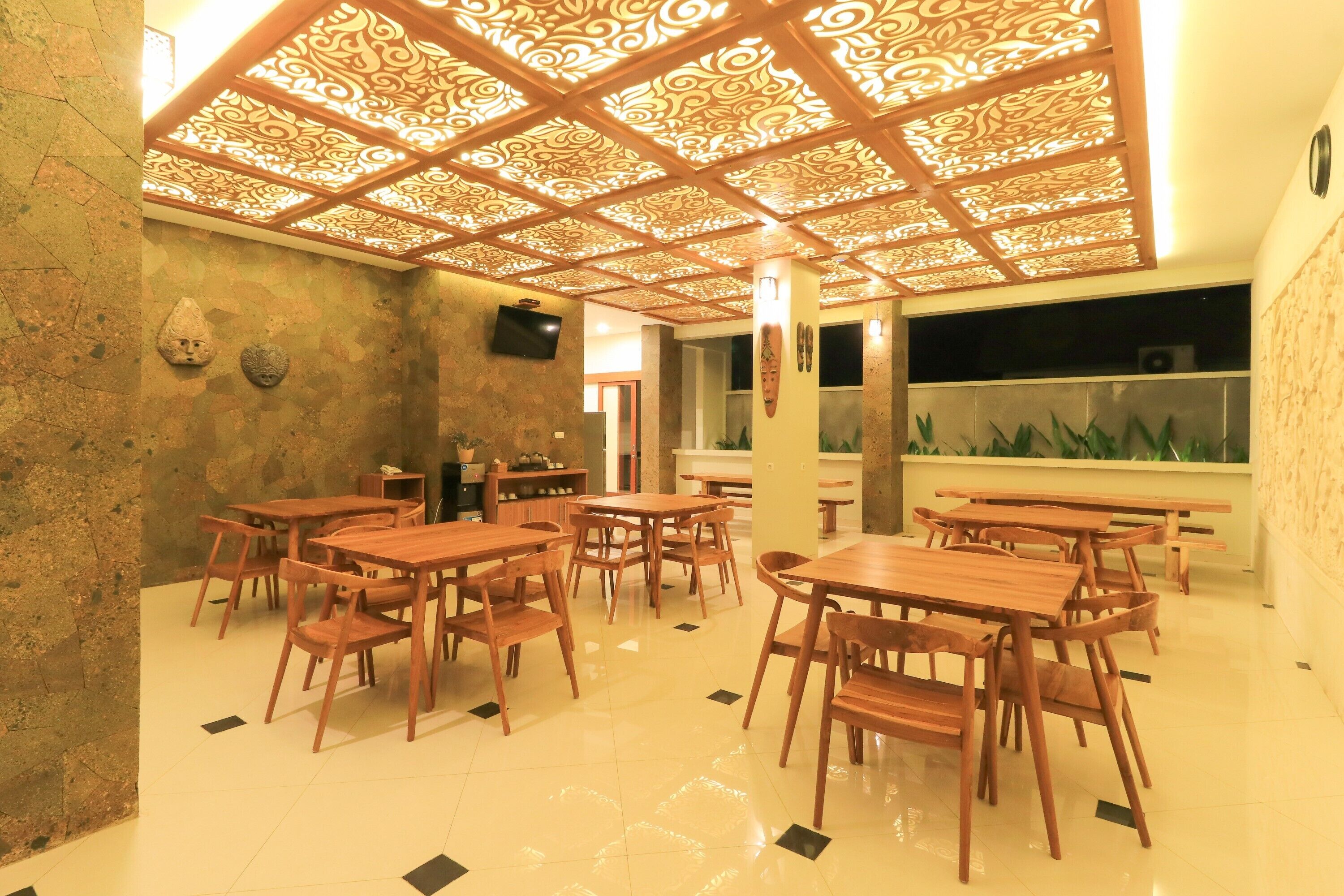 Un restaurante con mesas y sillas de madera, un techo decorativo y una pared de piedra.