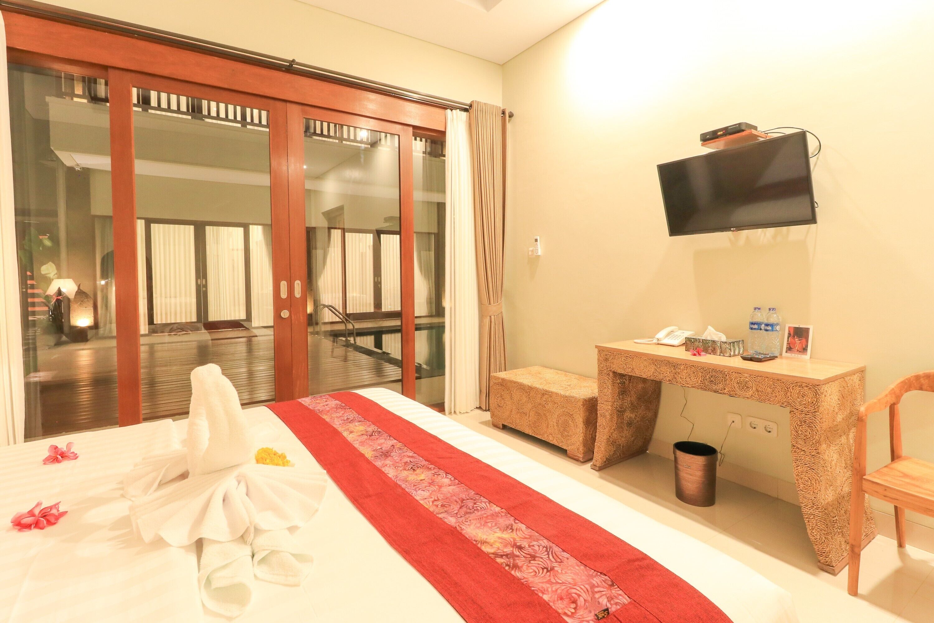 Habitación de hotel con cama, escritorio, silla, televisor y vistas al exterior.