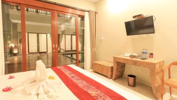 Habitación de hotel con cama, escritorio, silla, televisor y vistas al exterior.