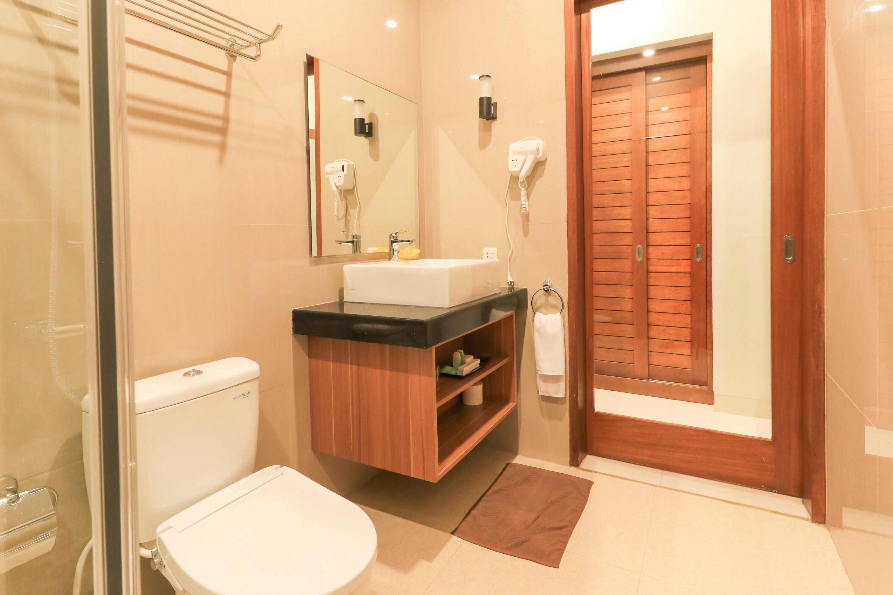 Un baño con inodoro, lavamanos, espejo y toallero.
