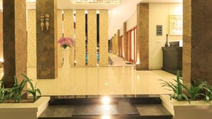 Una hall d'albergo con pavimento lucido, colonne decorative e una reception.
