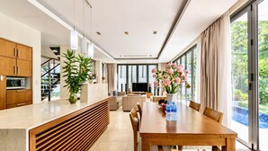A modern kitchen with wooden cabinets, a built-in oven, and a large window. - Ocean Villa Danang Beach (Da Nang)