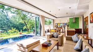 A modern living room with a pool, large windows, and a kitchen area. - Ocean Villa Danang Beach (Da Nang)
