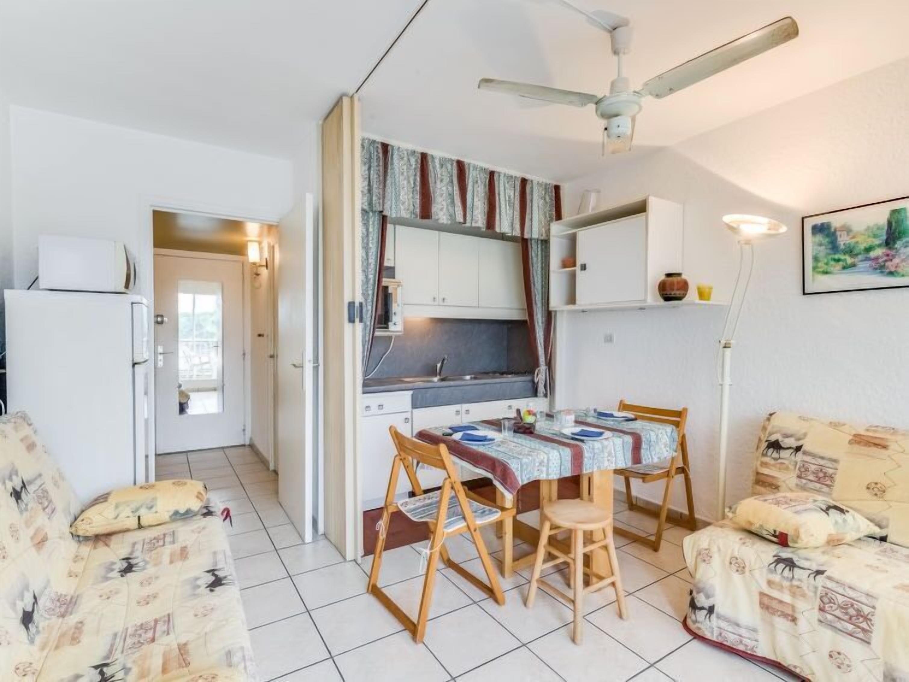Un espace de vie compact comprenant un coin cuisine, un coin repas avec une table et des chaises, et un canapé.
