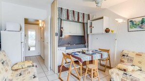 Un espace de vie compact comprenant un coin cuisine, un coin repas avec une table et des chaises, et un canapé.