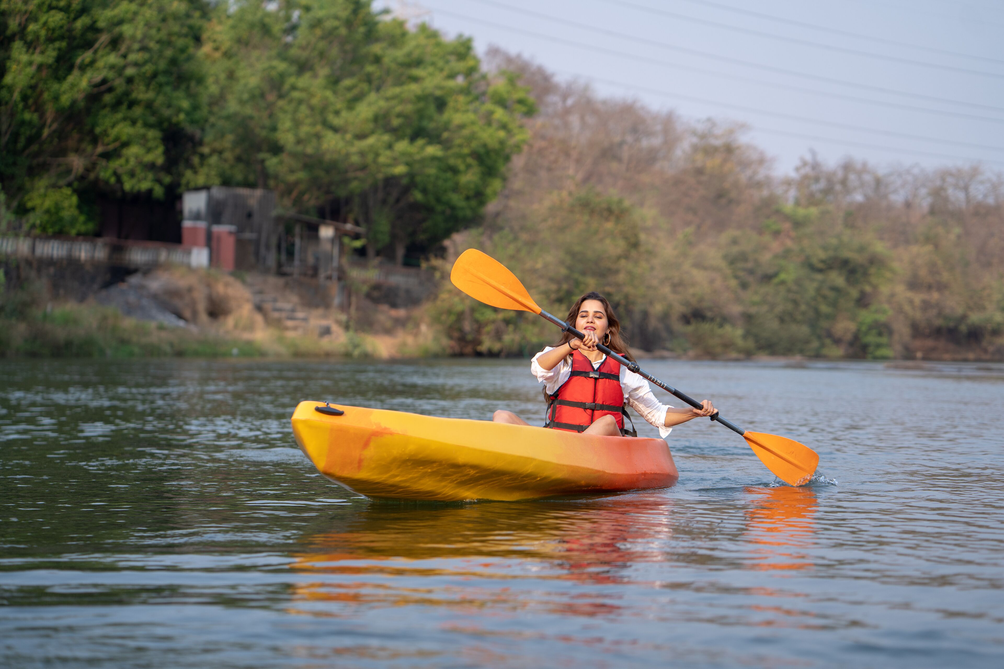 A person in a yellow kayak on a calm body of water.