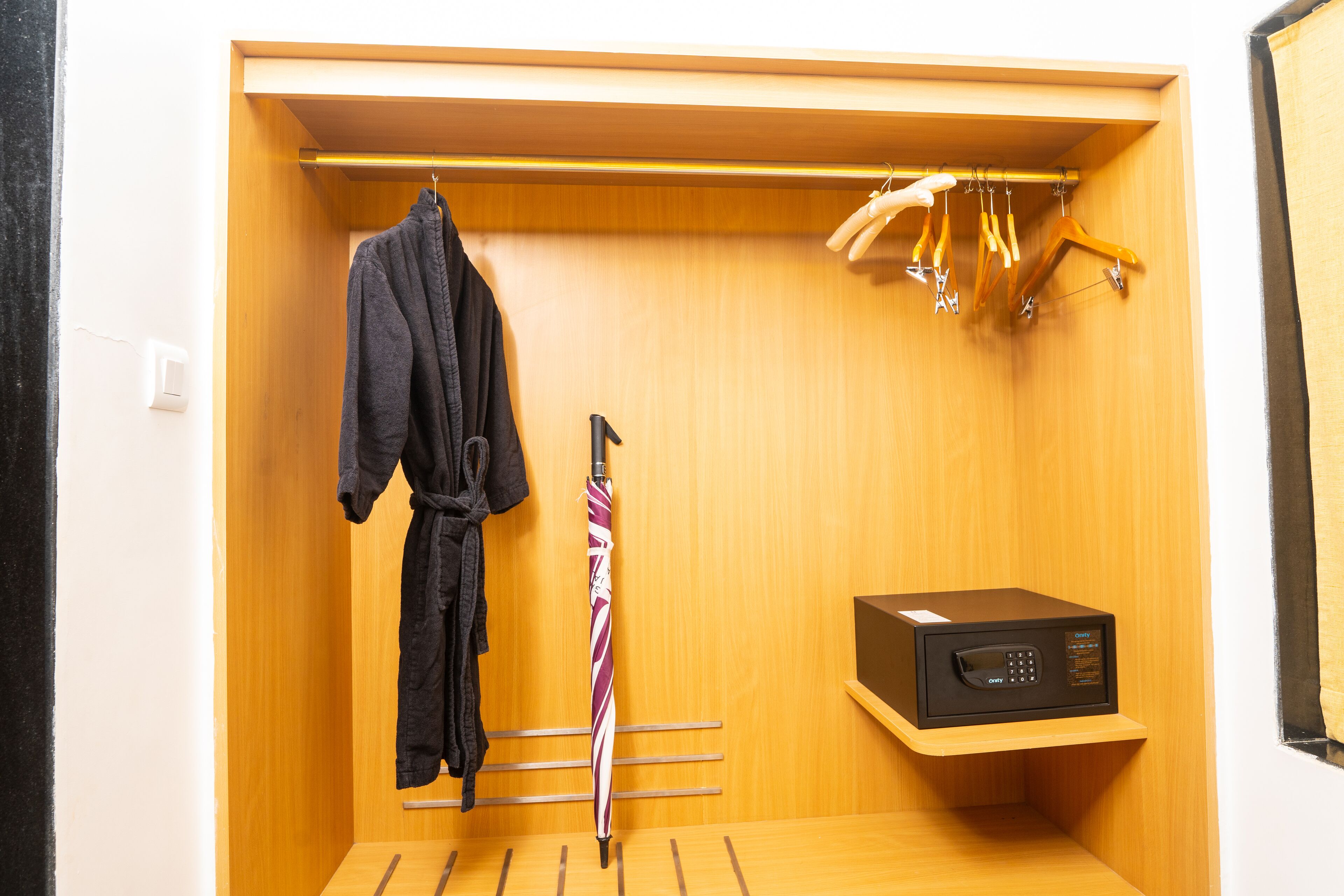 A walk-in closet with a wooden interior, a hanging rack, a robe, and a microwave on a shelf.