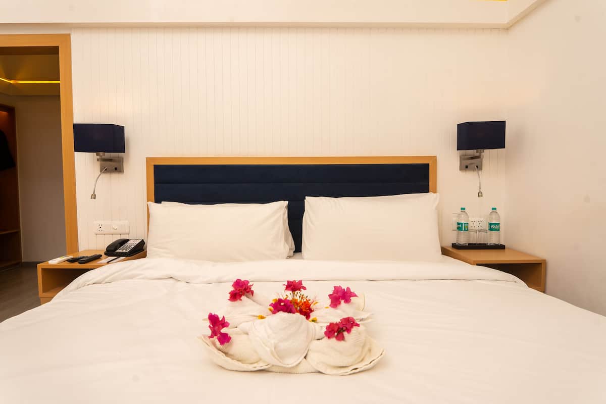 Habitación de hotel con cama, dos mesitas de noche, un teléfono y dos lámparas de pared.