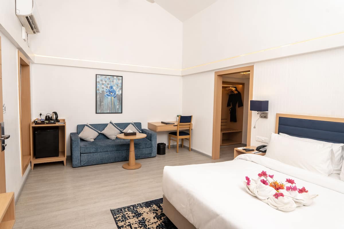Una habitación de hotel con cama, escritorio, sofá, una mesita y un armario.